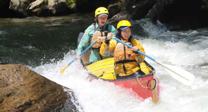 two gap year students paddle a canoe through whitewater on an outward bound expedition in north carolina 